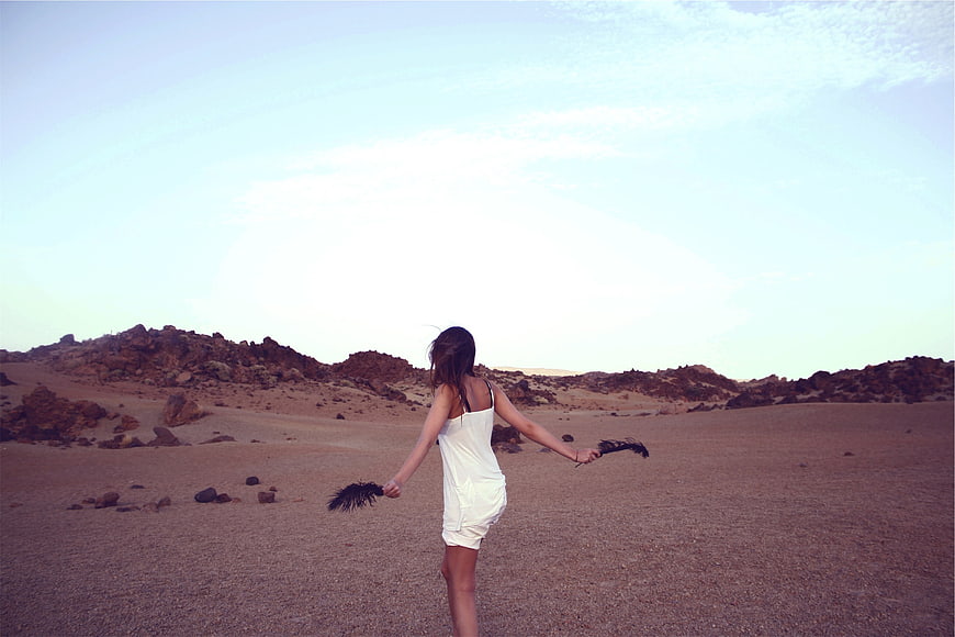 Woman with Feathers in Desert Landscape