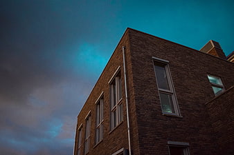 Low angle view of brick building against dramatic blue sky