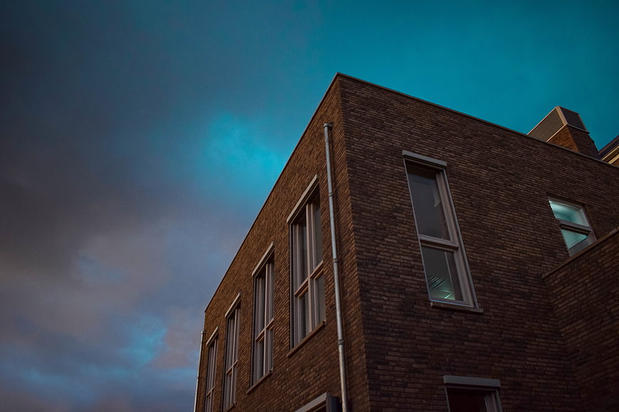 Low angle view of brick building against dramatic blue sky