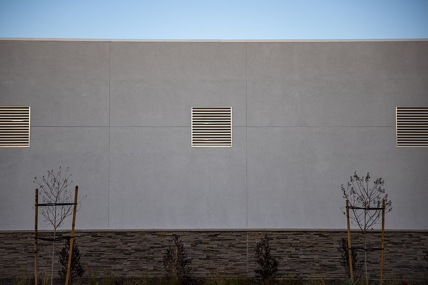 Minimalist modern building facade with gray wall and vents