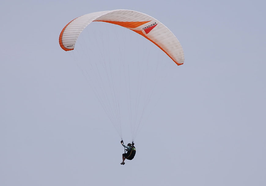 Paraglider soaring against a clear blue sky