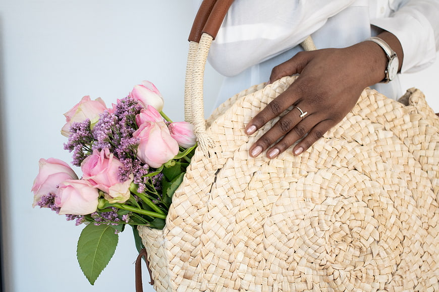 Woman holding woven straw bag with pink roses