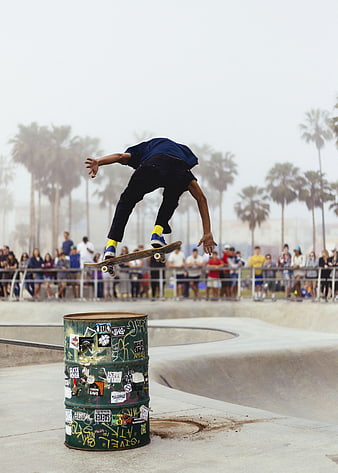 Skateboarder performing trick over barrel at skate park