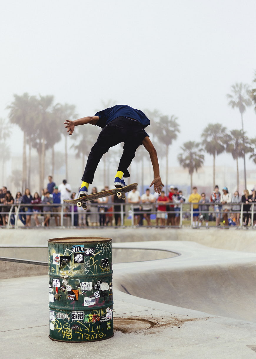 Skateboarder performing trick over barrel at skate park