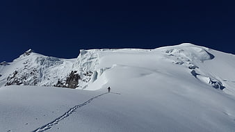 Lone skier ascending snowy mountain ridge in winter