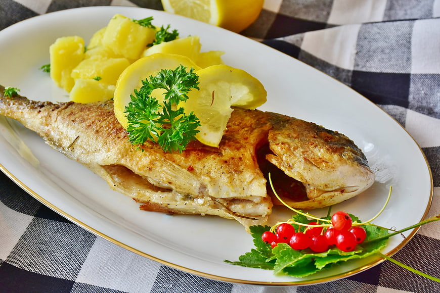 Grilled Sea Bream with Potatoes and Lemon on White Plate