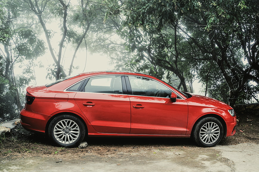 Red Sedan Parked in Misty Forest Setting