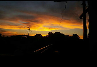 Dramatic sunset silhouette with power lines and trees