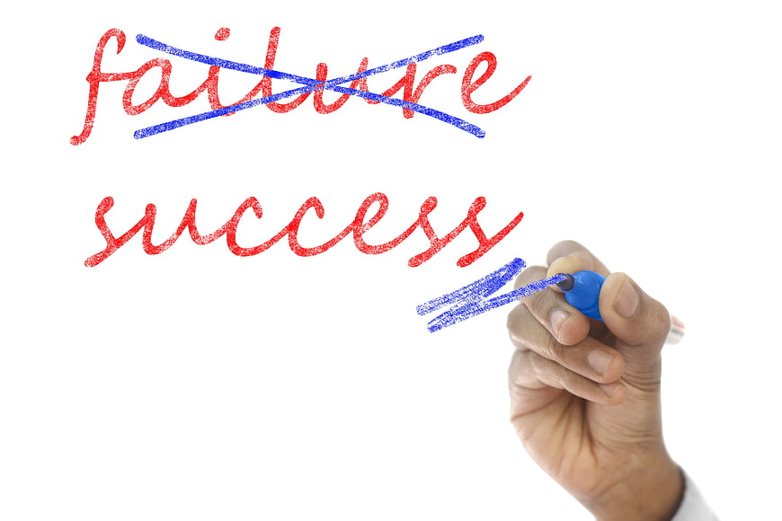 Hand crossing out failure and writing success on whiteboard