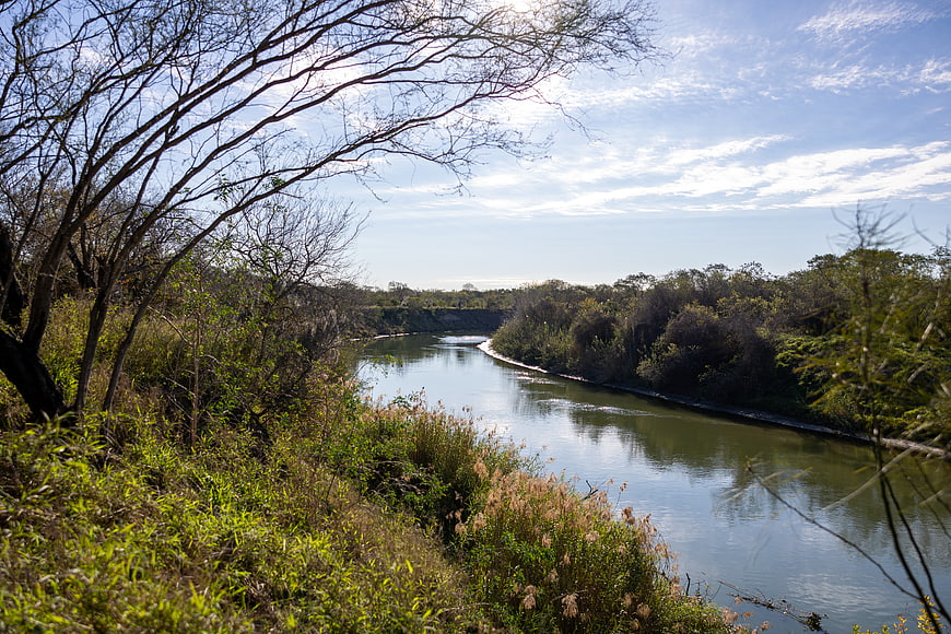 Serene River Landscape with Bare Trees and Blue Sky