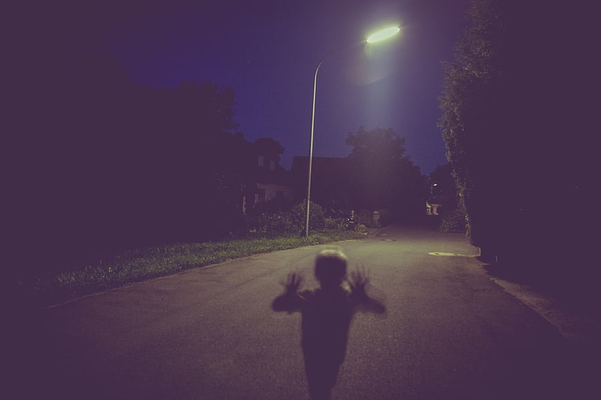 Spooky child silhouette on dark street at night