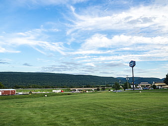 Green Meadow with Mountain Range and Blue Sky