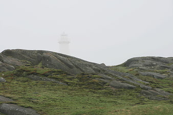 Misty Lighthouse on Rocky Coastal Landscape
