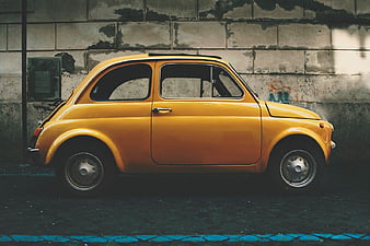 Vintage Yellow Fiat 500 Parked Against Urban Wall