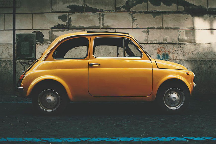 Vintage Yellow Fiat 500 Parked Against Urban Wall