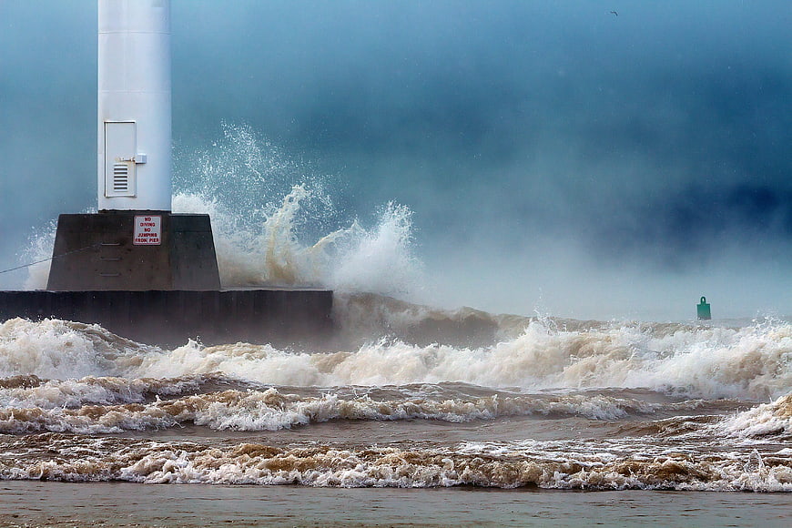 Stormy Ocean Waves Crashing Against Lighthouse Pier