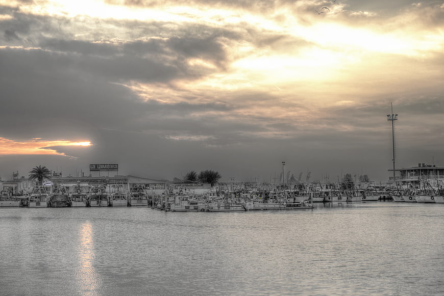 Fishing boats in harbor at sunset with dramatic clouds