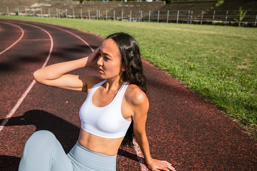 Tired female athlete resting on running track