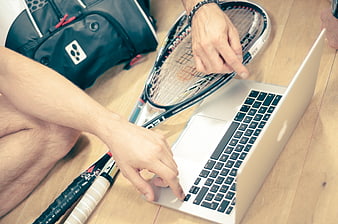 Squash player analyzing game on laptop with rackets