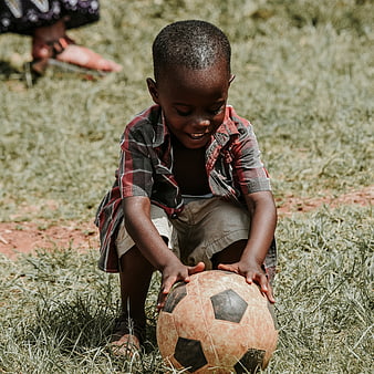 Young African Boy Playing with Soccer Ball on Grass