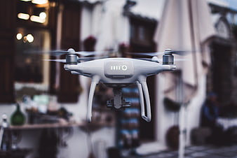 White drone hovering in front of blurred outdoor cafe background