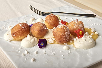 Golden fried dough balls with cream and edible flowers
