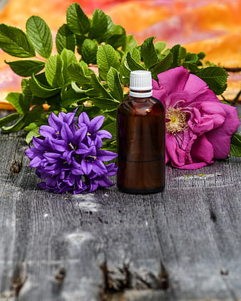 Aromatic Essential Oil Bottle With Purple And Pink Flowers On Rustic Wood