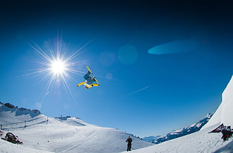 Snowboarder performing aerial flip against sunny blue sky