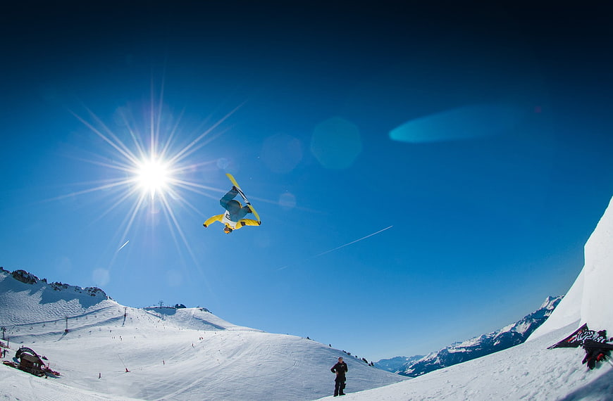 Snowboarder performing aerial flip against sunny blue sky