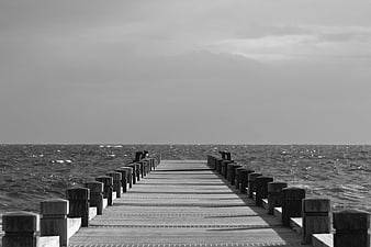 Black and white wooden pier extending into choppy ocean
