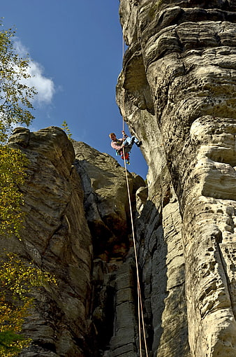 Rock climber rappelling down steep cliff face