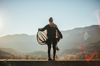Woman standing on mountain summit looking at sunrise