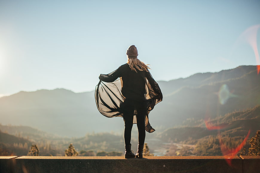 Woman standing on mountain summit looking at sunrise
