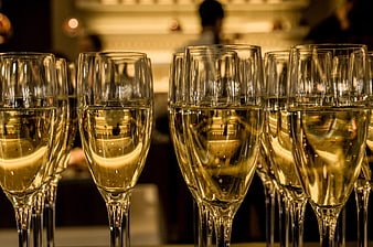 Row of Champagne Flutes with Golden Bubbles in Dimly Lit Bar