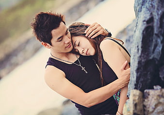 Romantic Asian couple embracing outdoors near rocks