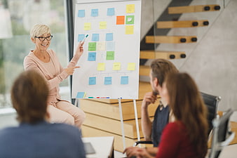 Senior woman presenting strategy with sticky notes to team