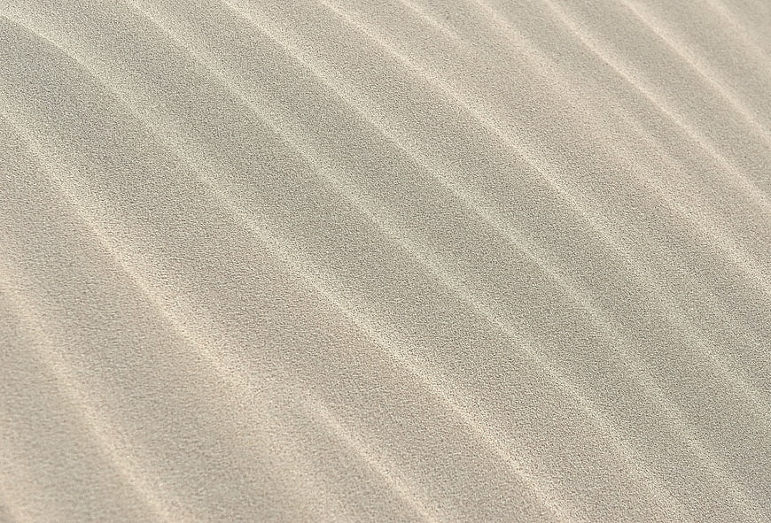 Close-up texture of rippled sand dunes with natural patterns