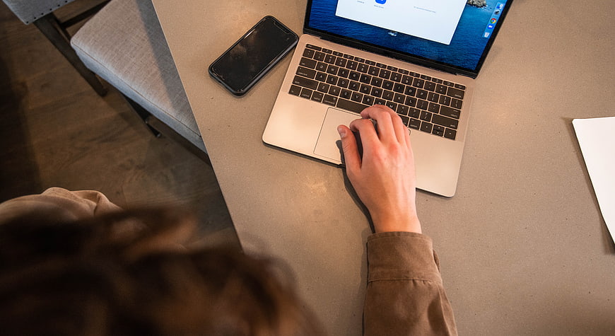 Overhead view of hand using laptop trackpad at desk