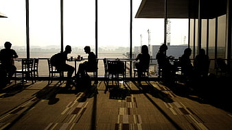 Silhouettes of travelers waiting in airport terminal cafe