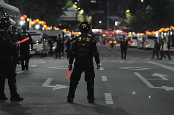 Police Officer in Riot Gear Standing on Street at Night