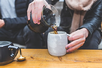 Pouring Coffee into Ceramic Mug on Wooden Table