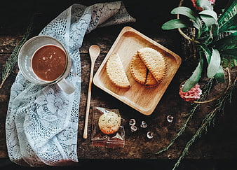 Flat lay of hot chocolate, biscuits, and lace on rustic wood