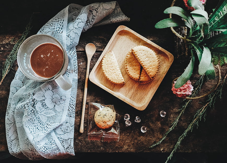 Flat lay of hot chocolate, biscuits, and lace on rustic wood