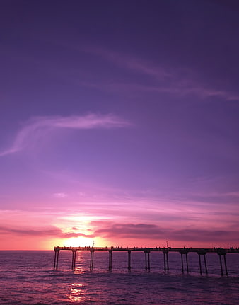 Silhouette of pier at sunset with purple and pink sky