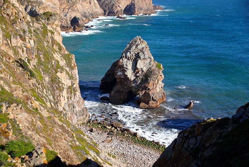 Dramatic coastal rock formation with arch in blue ocean