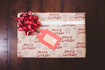 Christmas gift box with red bow on wooden table