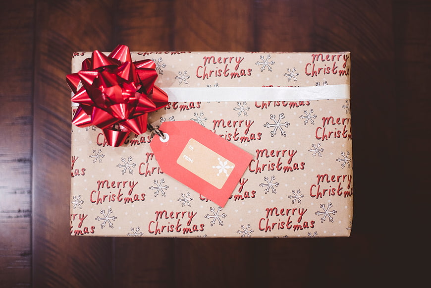 Christmas gift box with red bow on wooden table