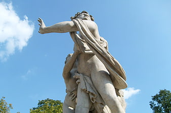 Low angle view of classical stone sculpture against blue sky