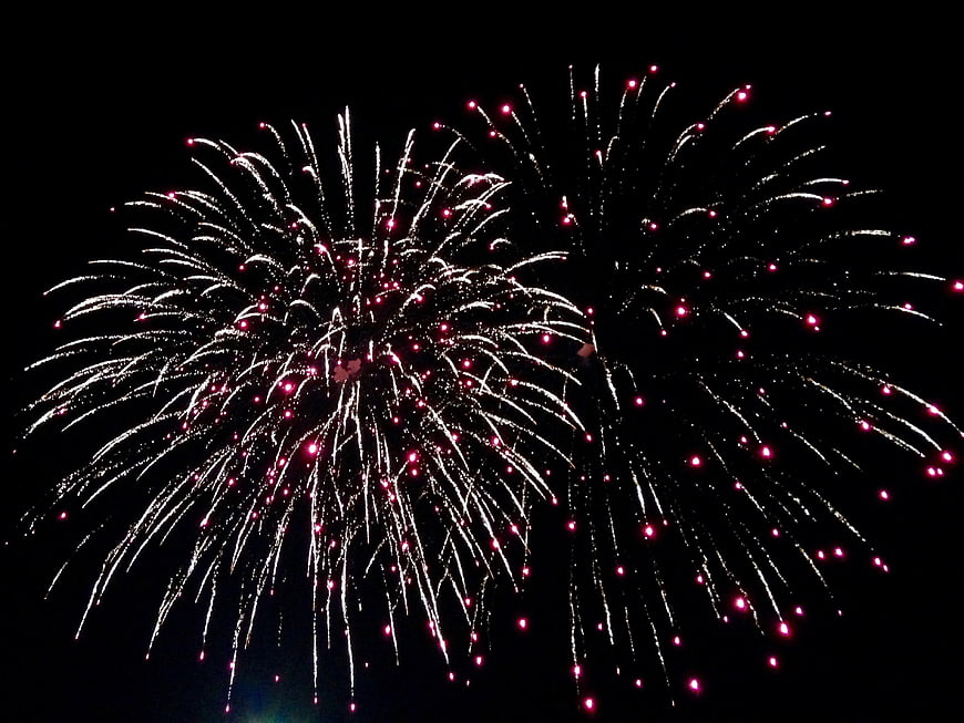 Red and white fireworks bursting in the night sky