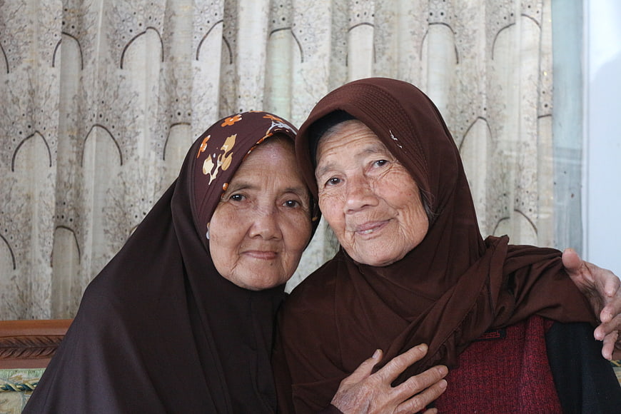 Portrait of Two Elderly Women Wearing Headscarves Smiling Together Indoors